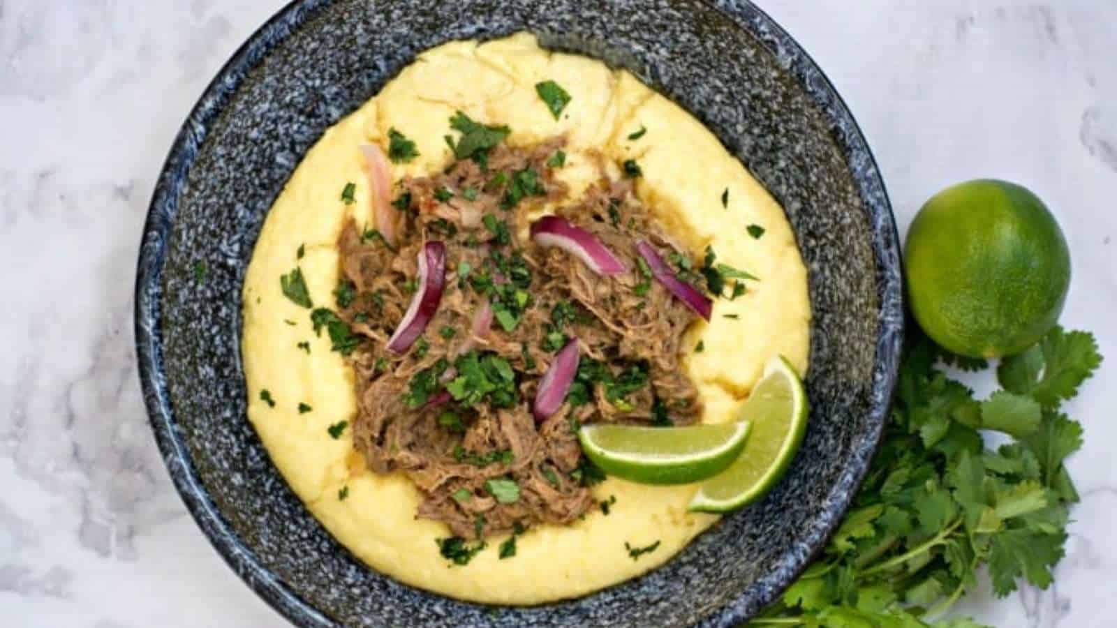 A bowl of polenta with meat and garnishes.