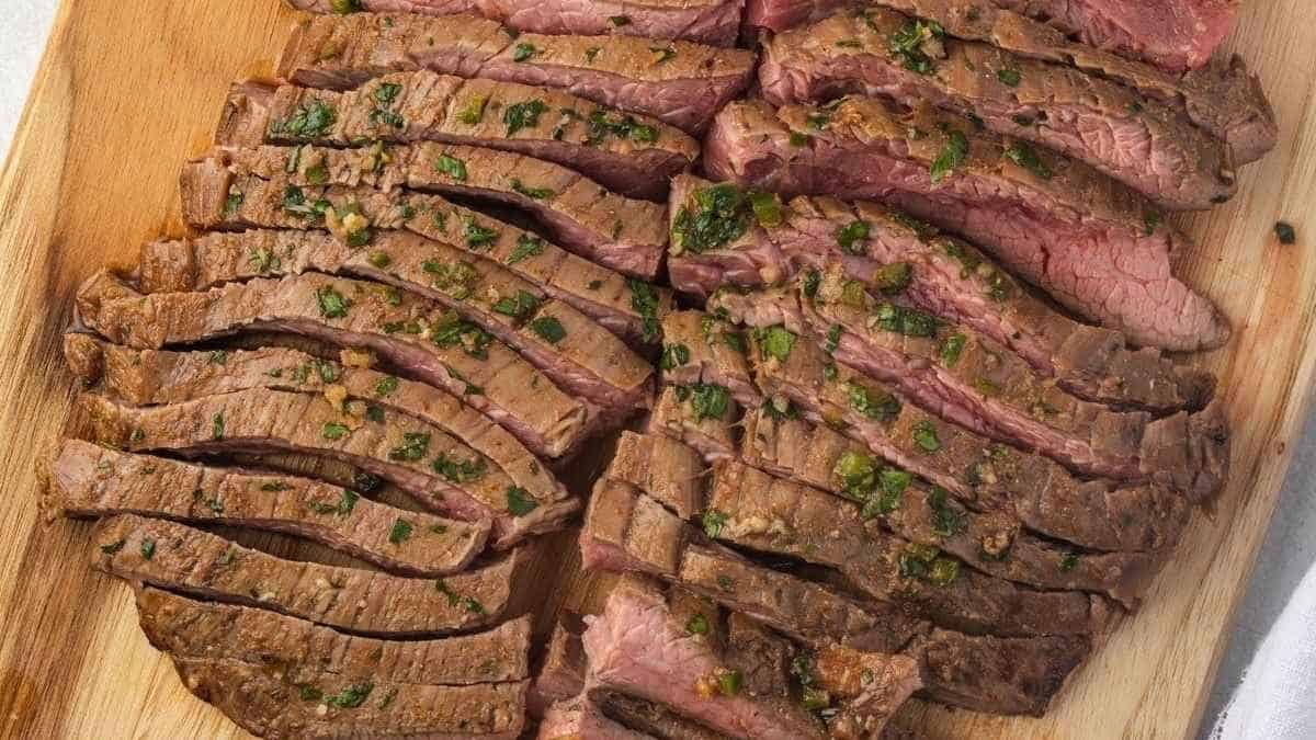 Sliced steak on a wooden cutting board.