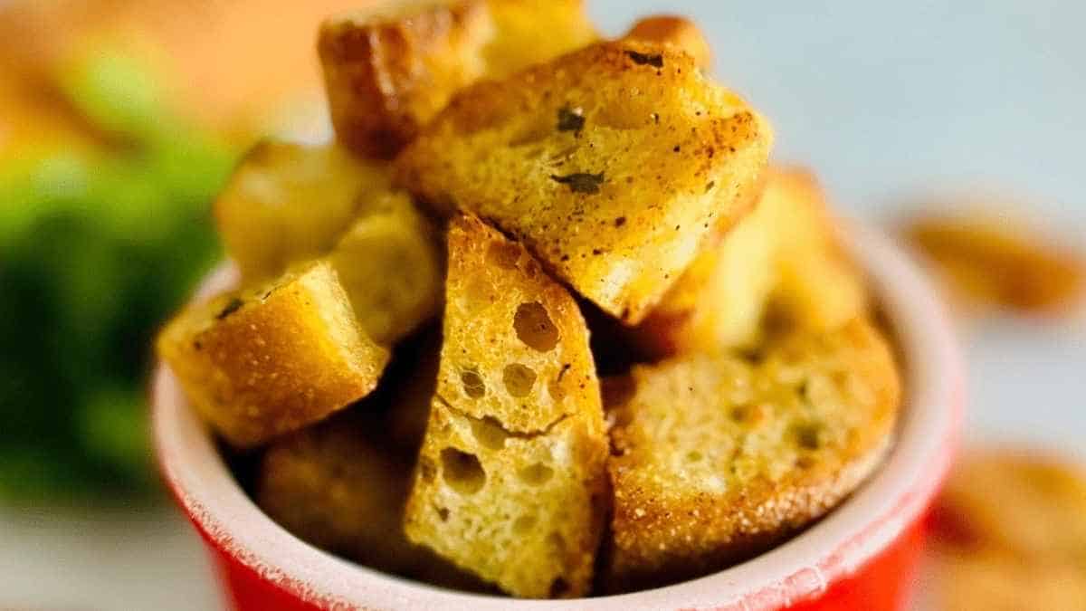 Croutons in a red bowl with parsley.