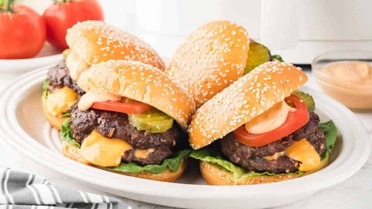 Four burgers on a plate next to a slow cooker.