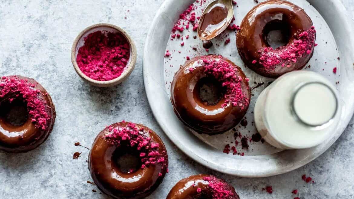 Chocolate donuts with pink sprinkles on a plate.