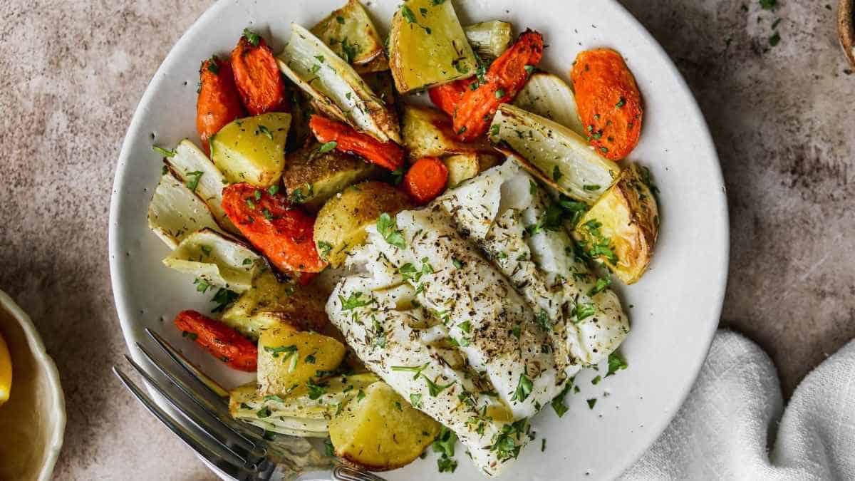A plate of fish with potatoes and carrots.