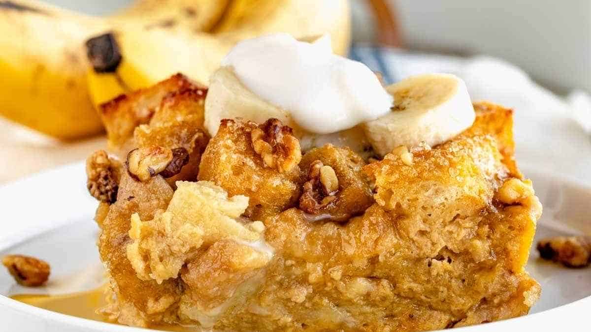 Banana bread pudding topped with whipped cream and bananas.