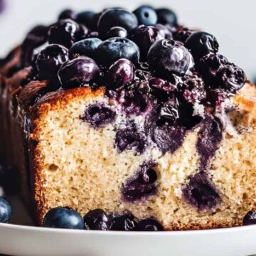 A slice of blueberry cake on a white plate.
