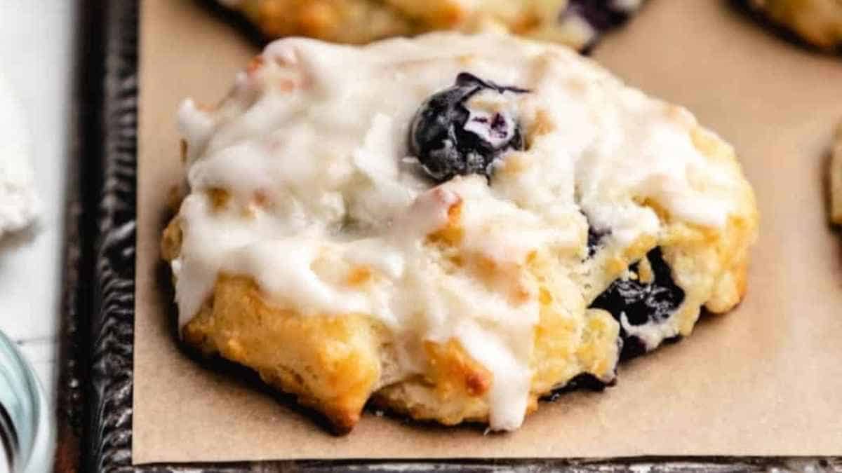 Blueberry scones with icing on a baking sheet.