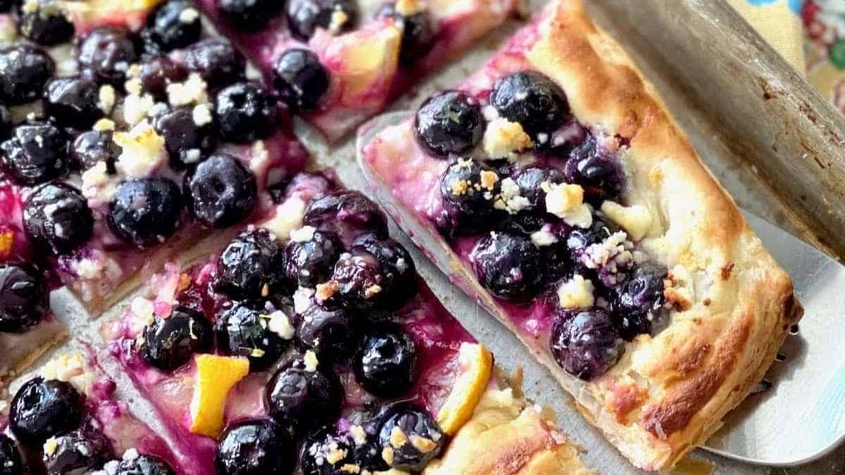 A blueberry and orange pizza on a baking sheet.