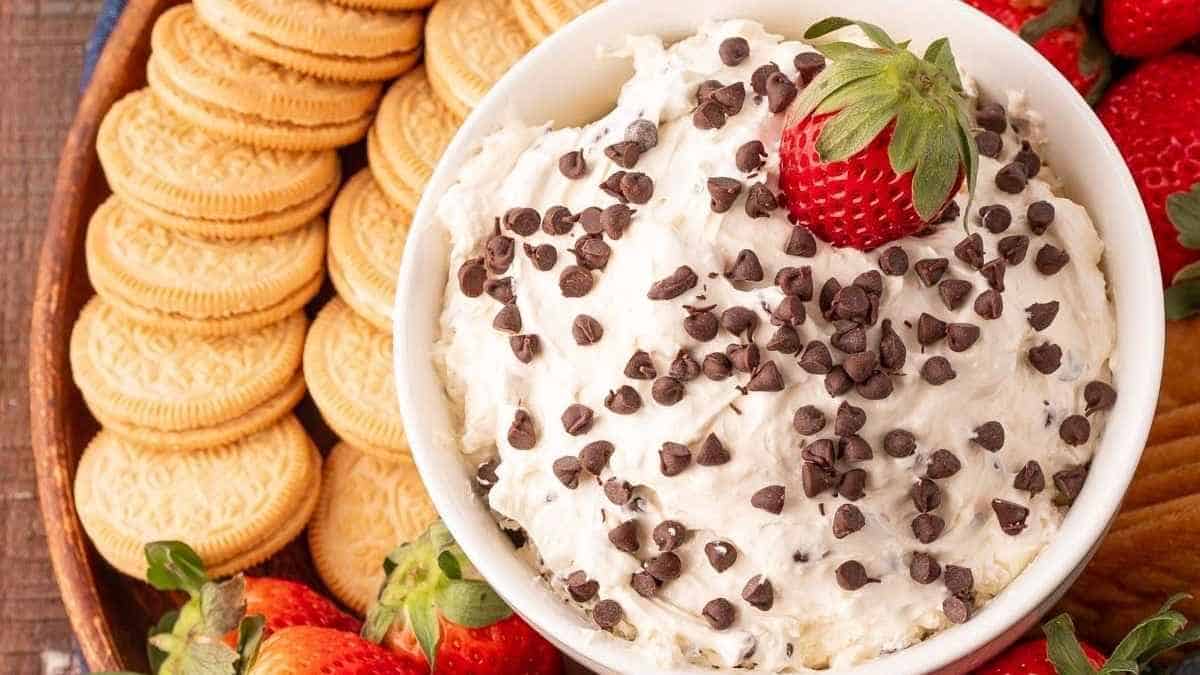 A bowl of chocolate chip cookie dough dip with strawberries and crackers.