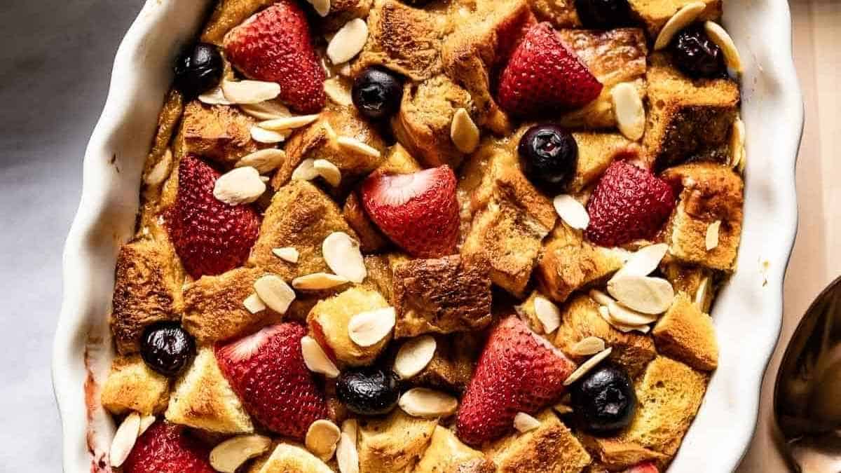 A dish of french toast casserole with berries and almonds.