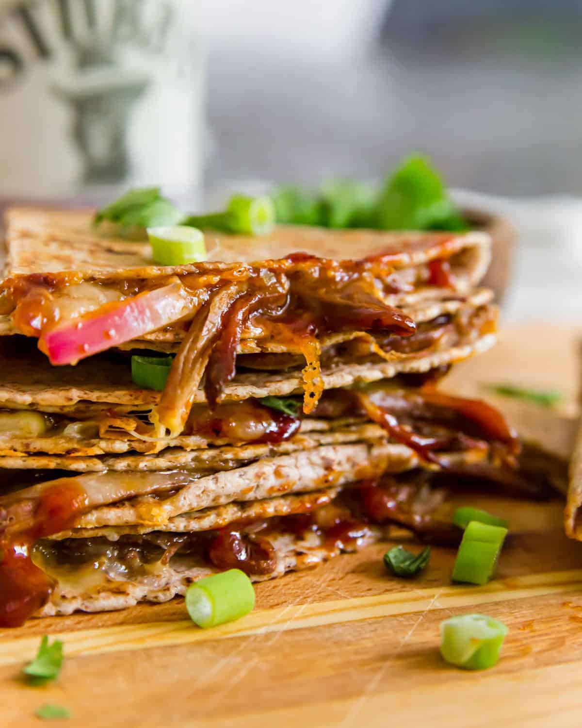 A stack of bbq pulled pork quesadillas on a cutting board.