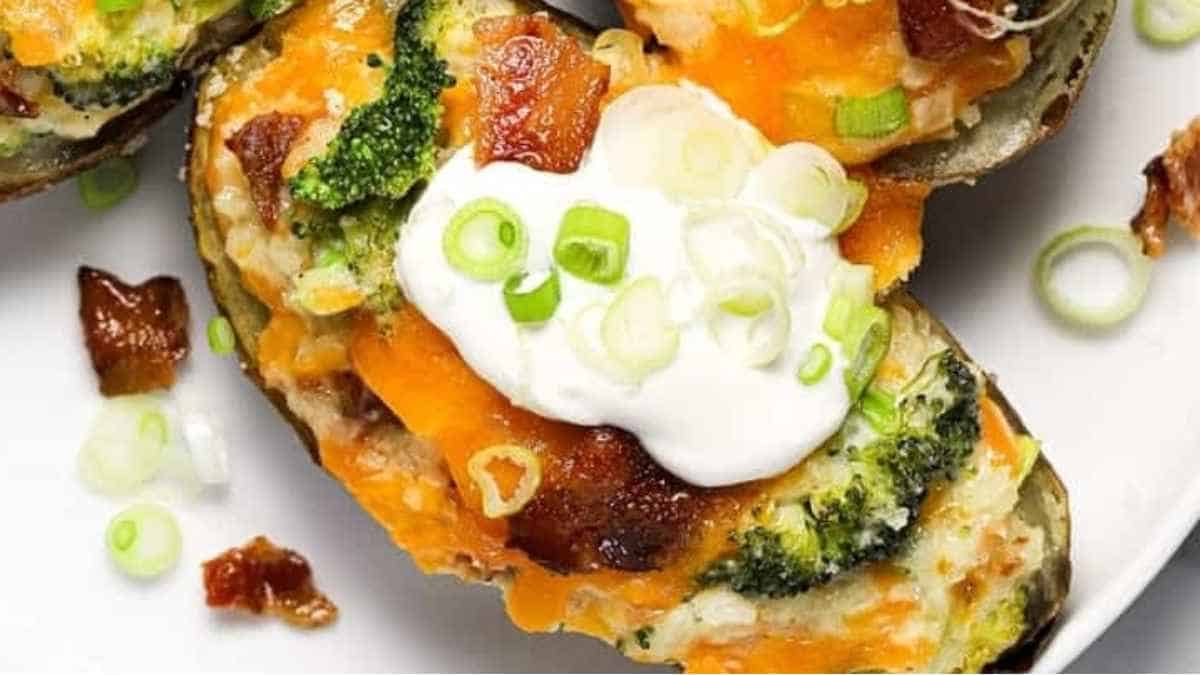 A plate of baked potatoes with broccoli and sour cream.