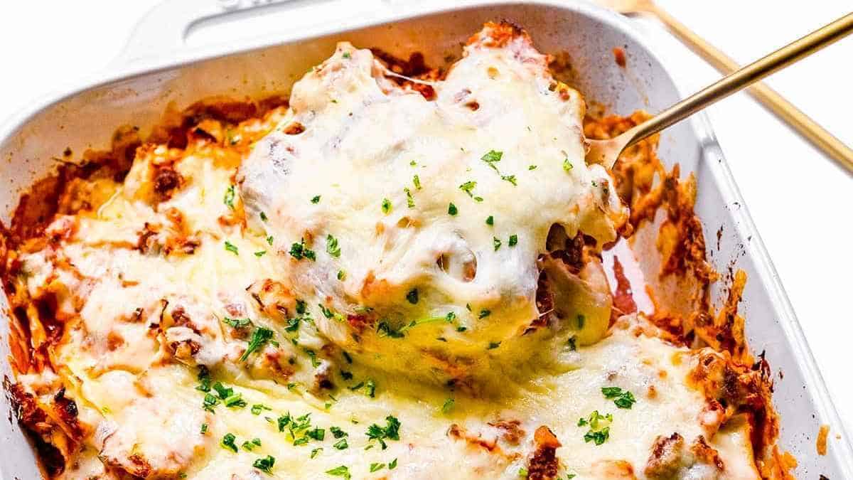 Lasagna in a white baking dish with a fork.