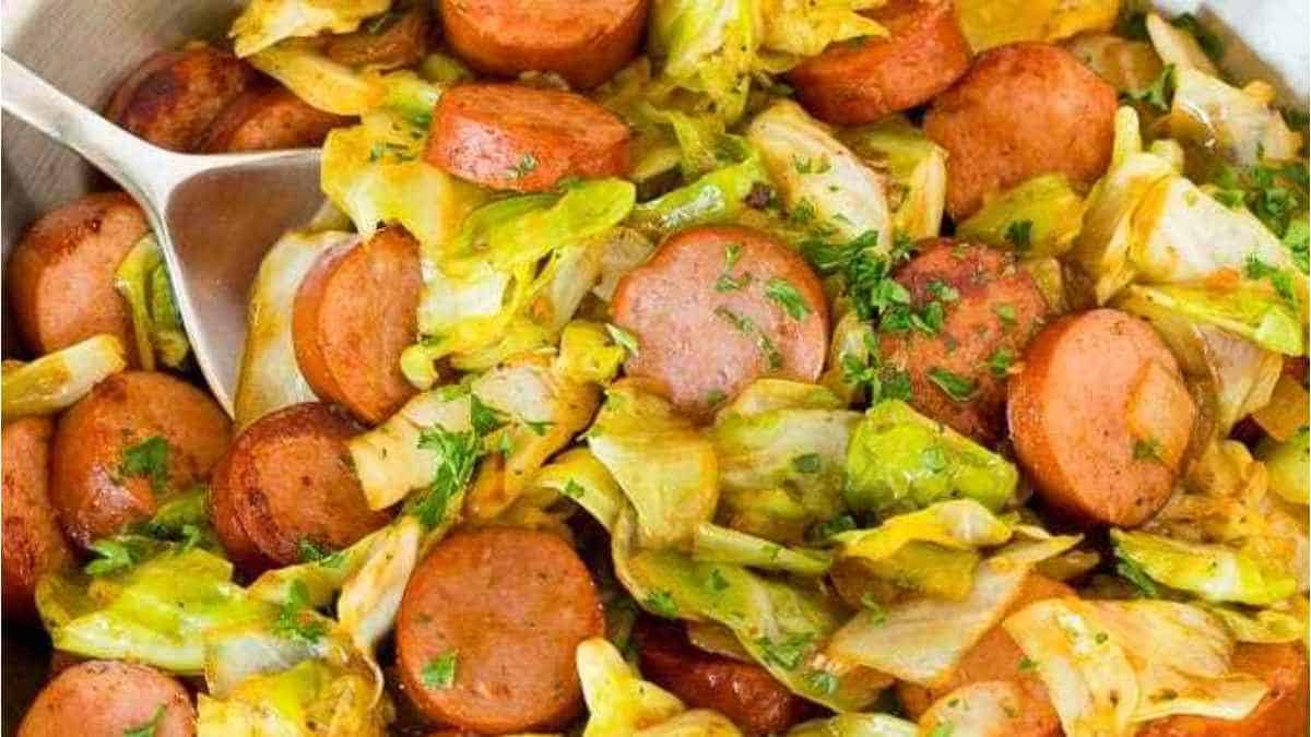 Sausage and cabbage in a skillet with a spoon.