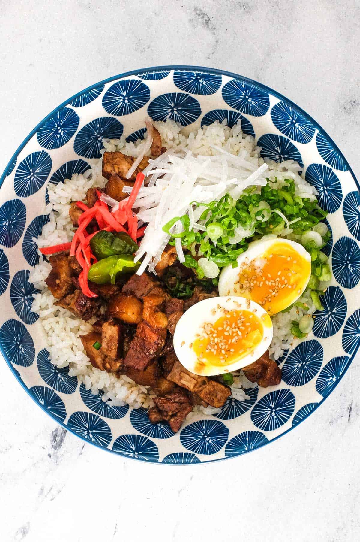 A bowl of delicious pork belly recipes on a marbled surface.