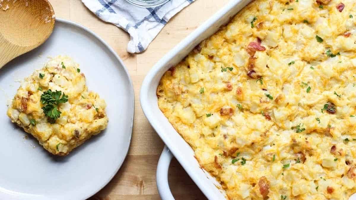 A casserole dish with ham and potatoes and a wooden spoon.