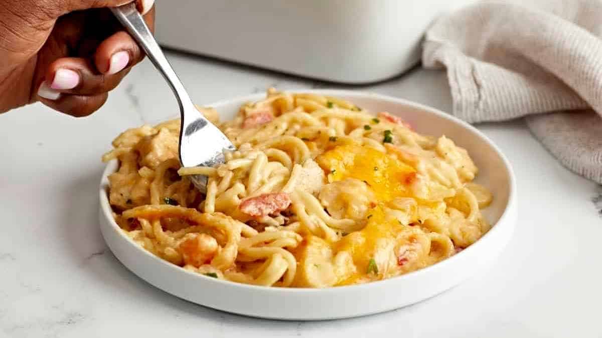 A person holding a fork over a bowl of pasta.