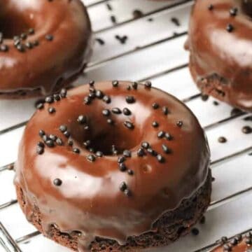 Chocolate donuts on a cooling rack with black sesame seeds.