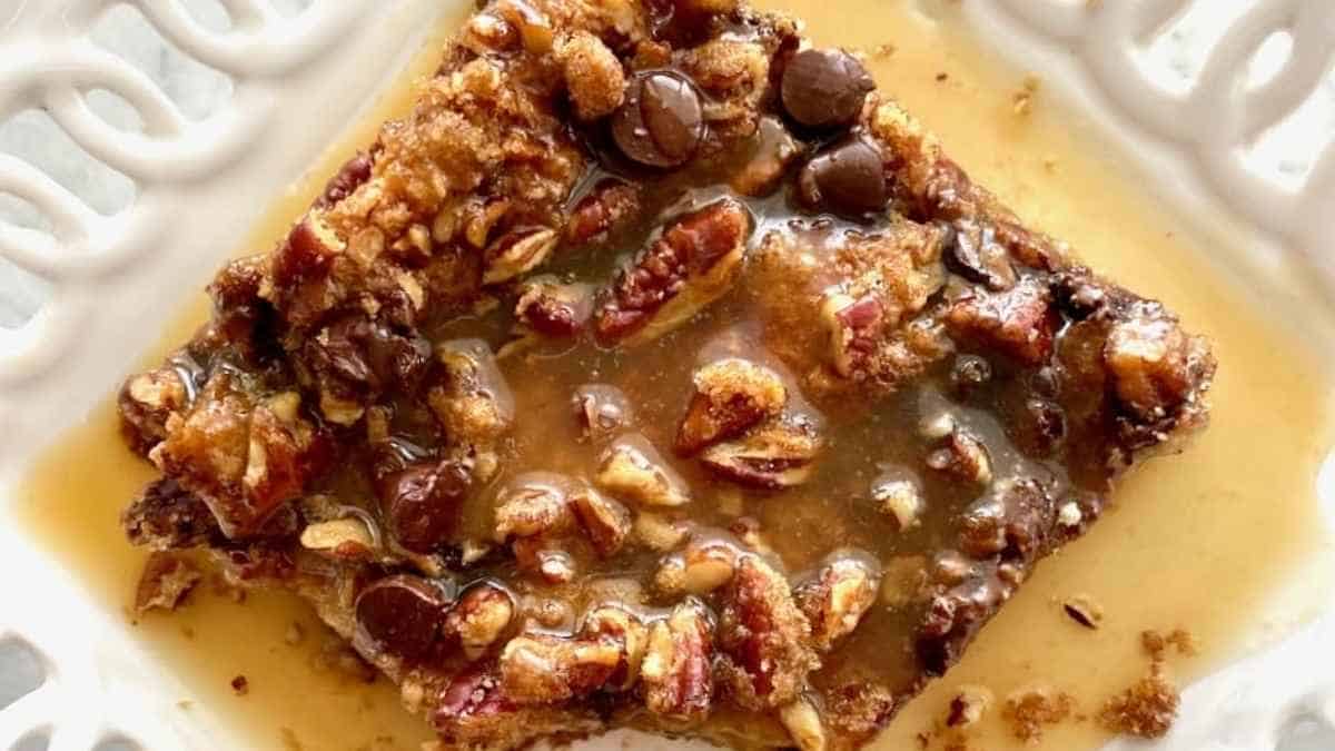 A slice of oatmeal with caramel and pecans on a white plate.