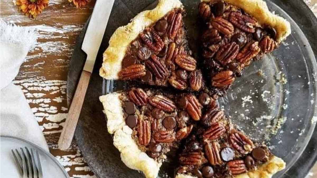 A pie with pecans and chocolate on a plate.