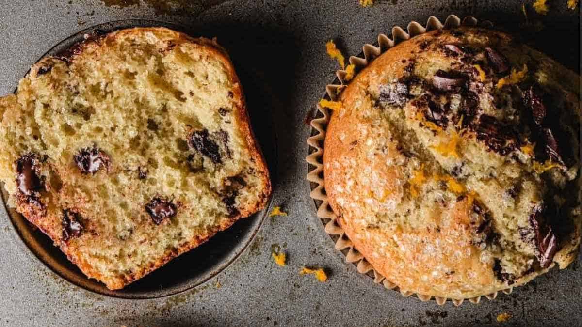 Two muffins with chocolate chips on a baking sheet.