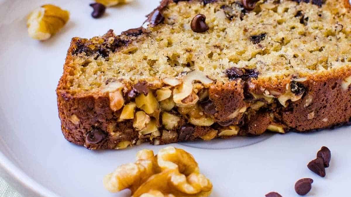 A slice of banana bread with walnuts on a plate.