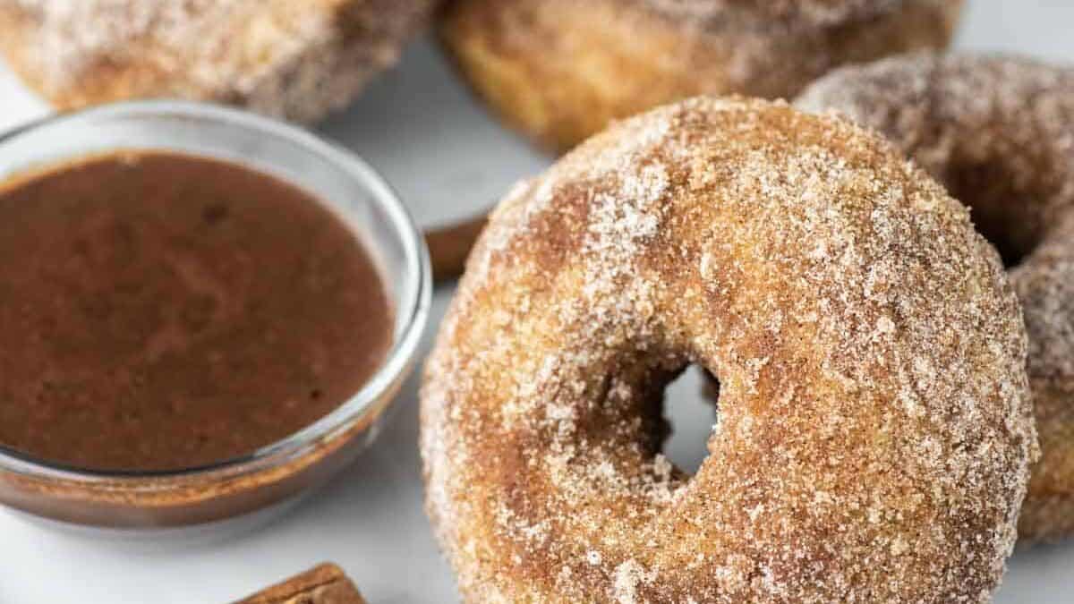 Cinnamon sugar donuts on a plate with a cinnamon dipping sauce.