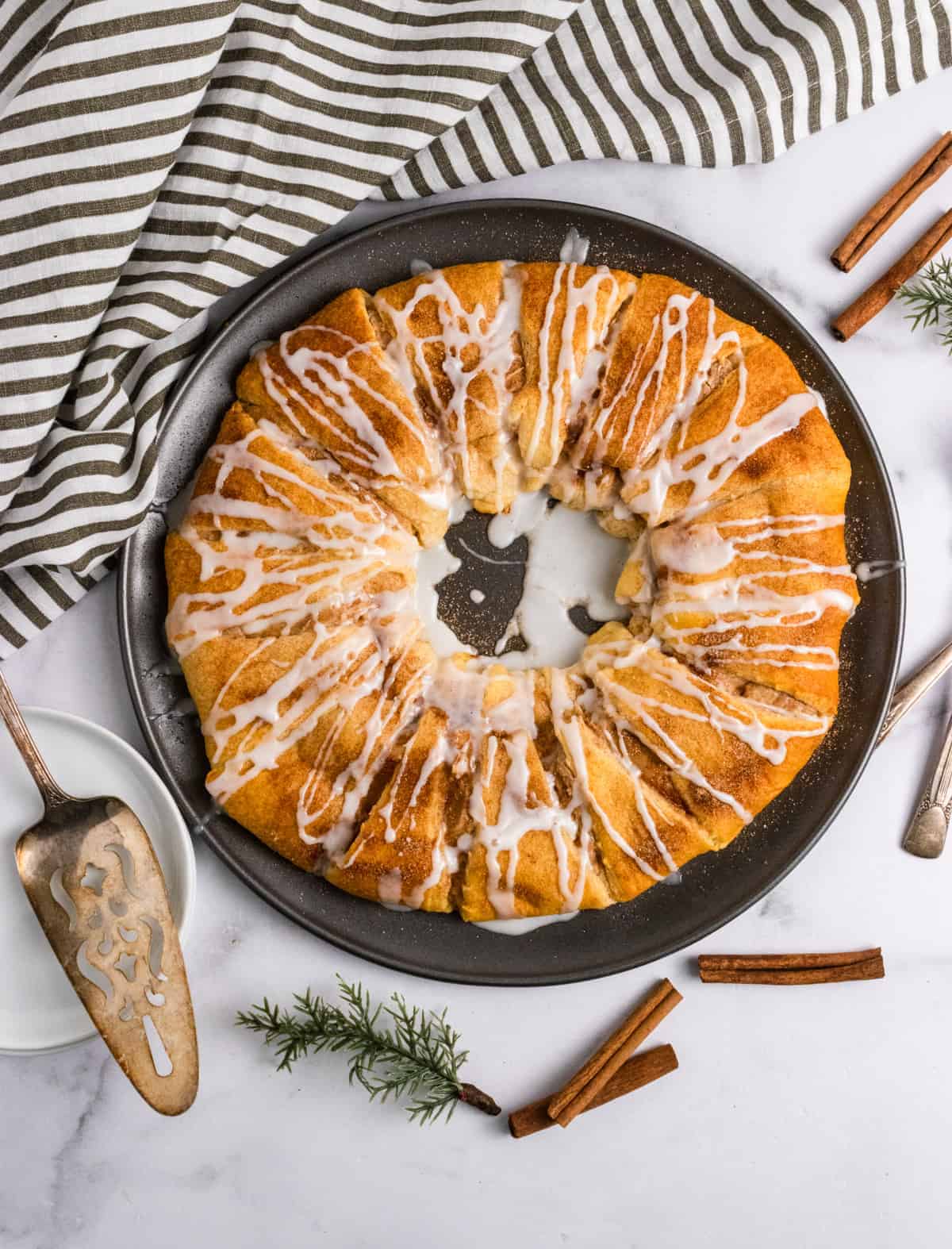 Crescent roll wreath with cinnamon and icing on pan. 

