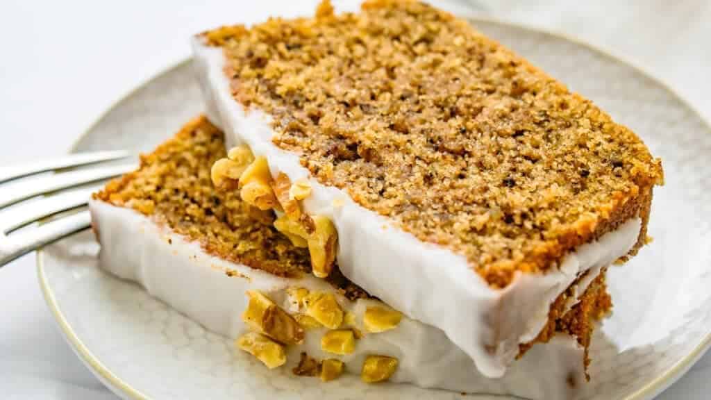 A slice of carrot cake on a plate with a fork.