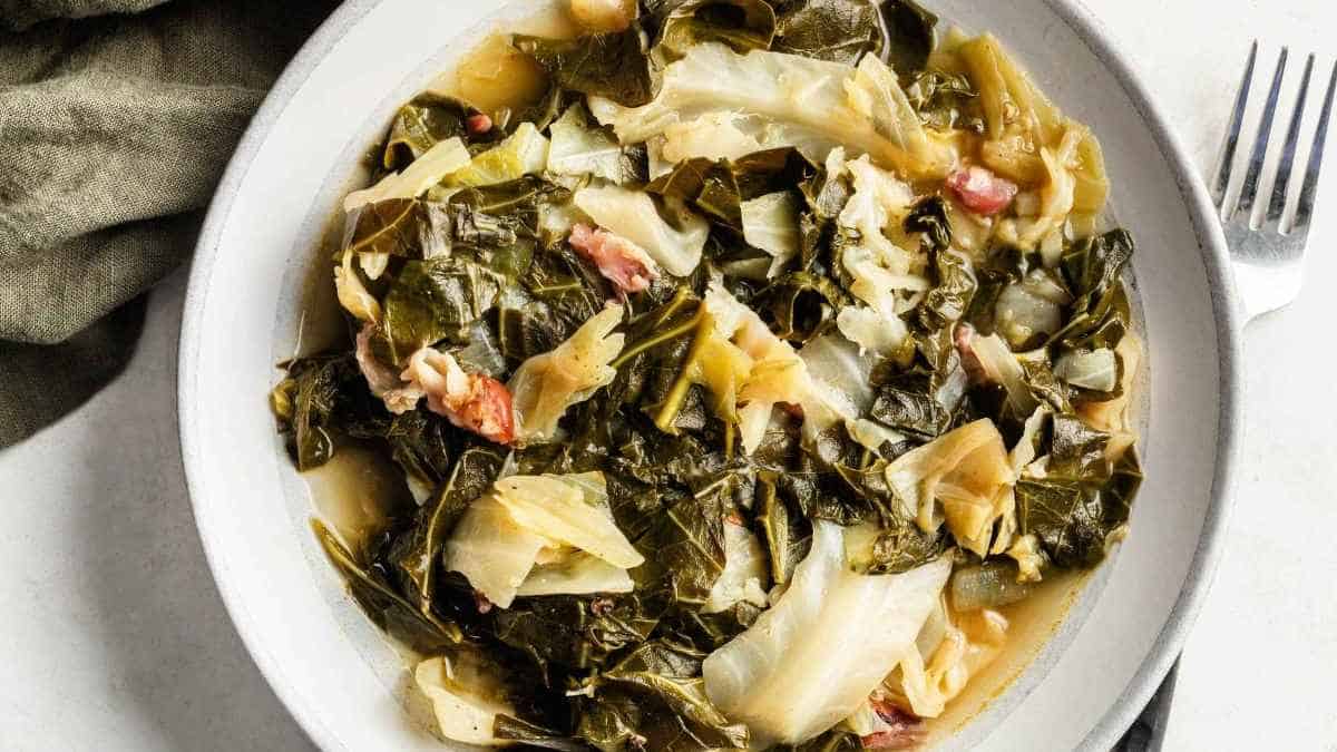 A plate of collard greens with bacon and a fork.