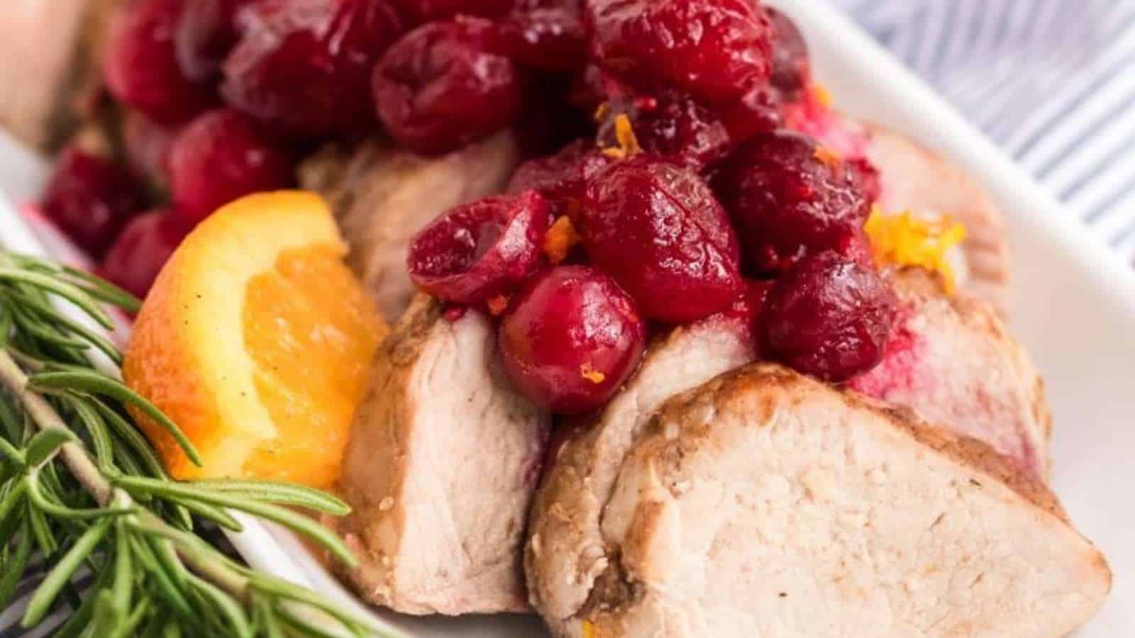 Pork tenderloin with cranberry sauce on a white plate.