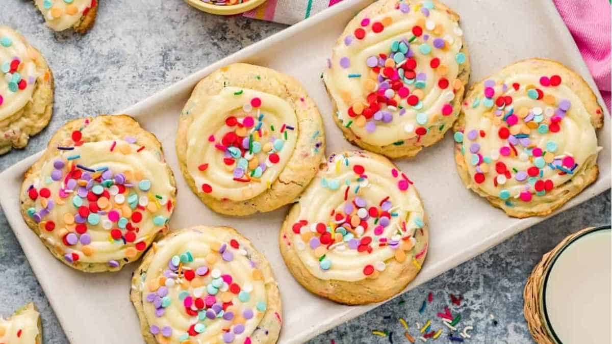 A plate of cookies with sprinkles and milk.