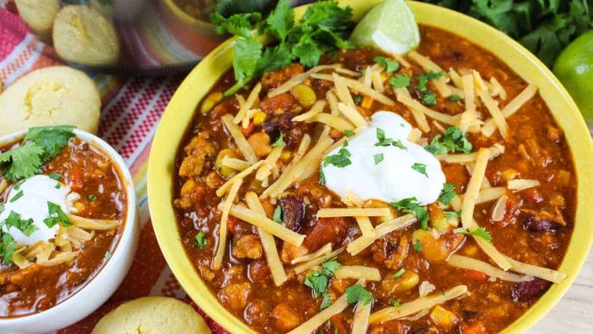 A bowl of chili with sour cream and tortilla chips.