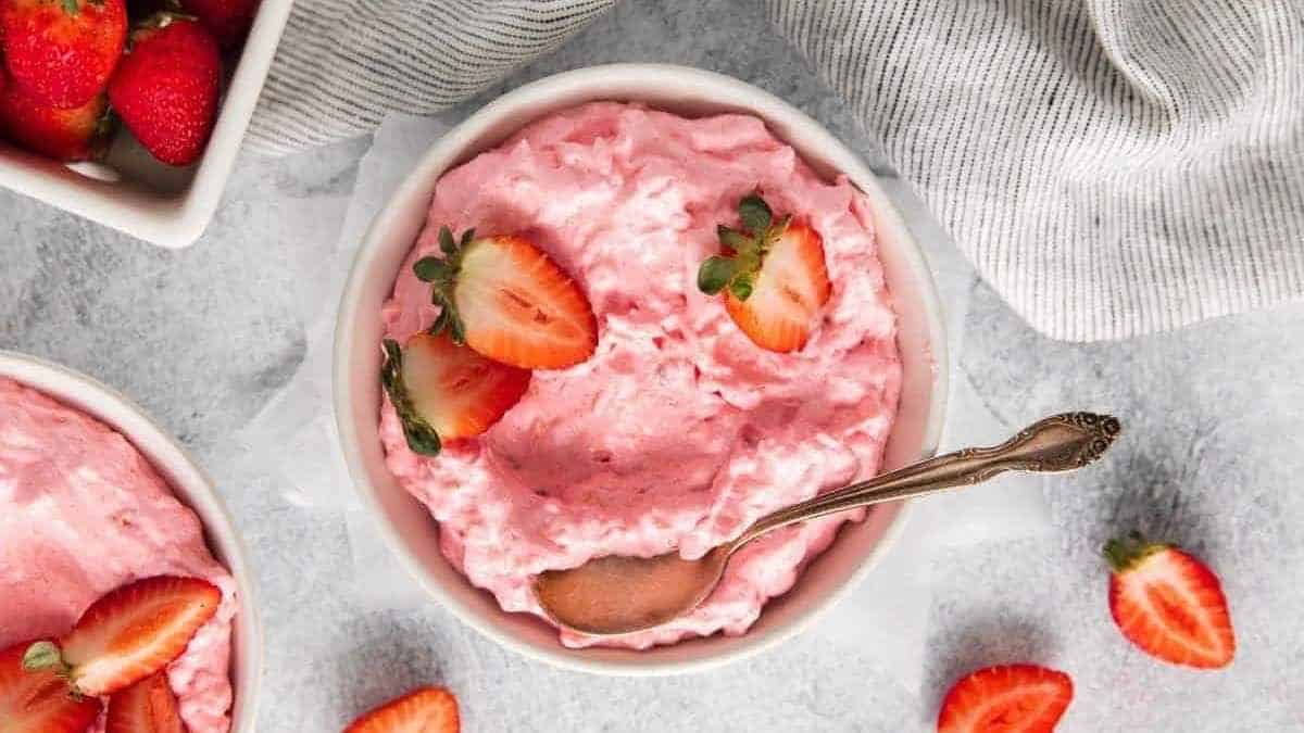 A bowl of strawberry ice cream with a spoon.