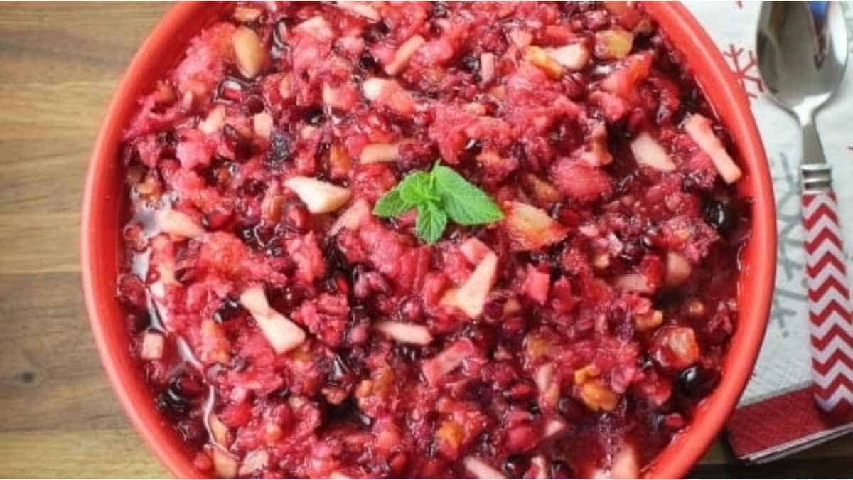 Cranberry sauce in a red bowl with a spoon.