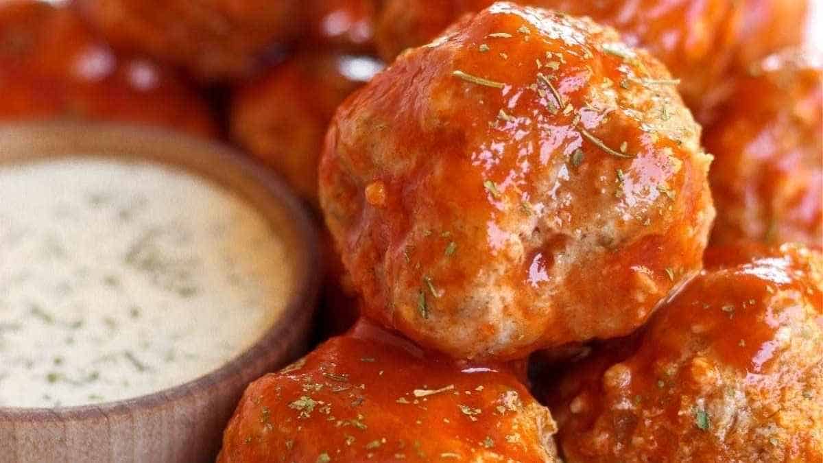 A bowl of meatballs with sauce and dipping sauce.