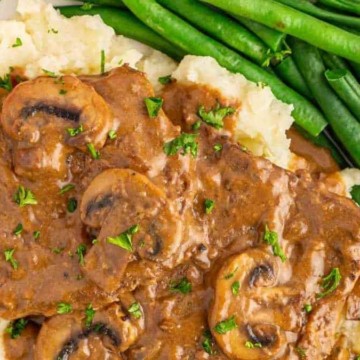 A plate of beef gravy with mushrooms and green beans.