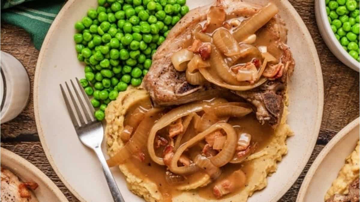 Pork chops with gravy and peas on a plate.