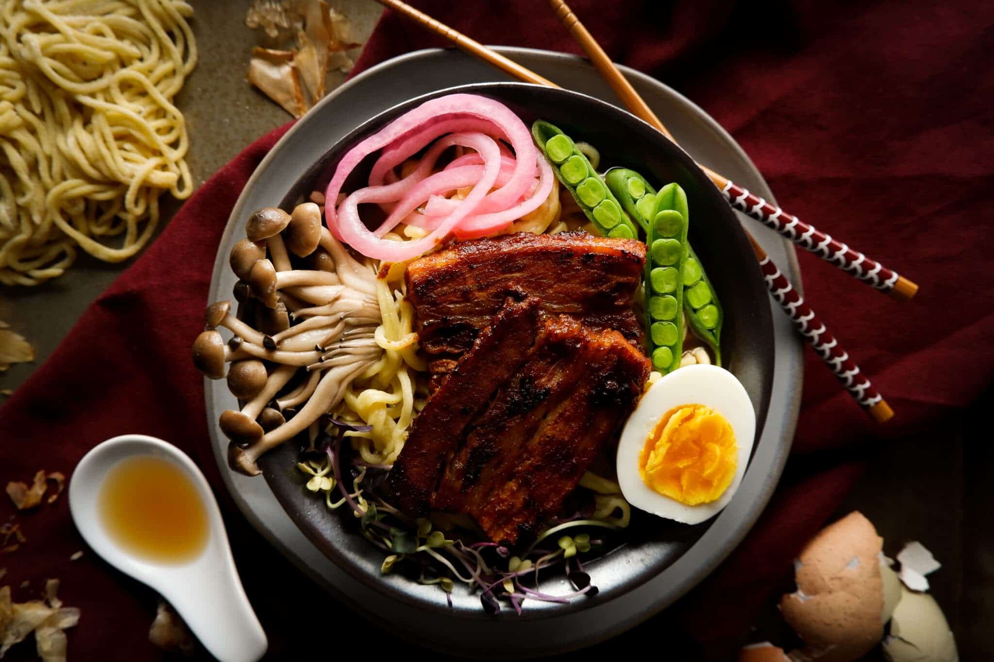 A bowl of Asian noodle soup with pork belly and vegetables.