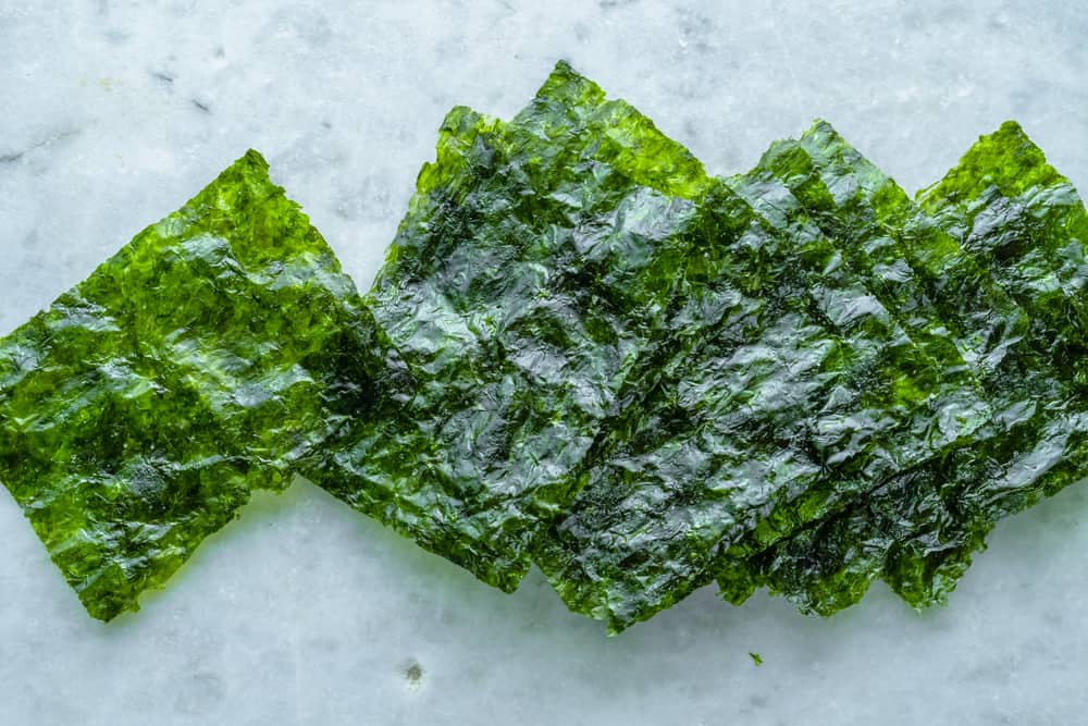 A pile of green seaweed on a marble surface.