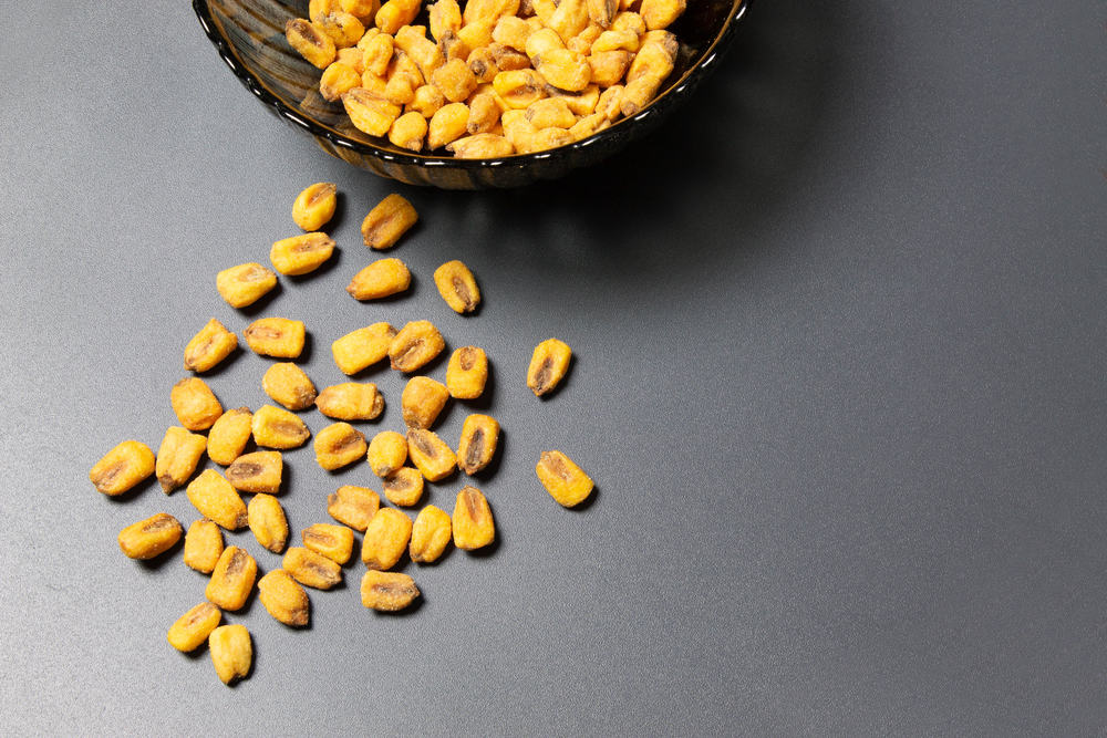 A bowl full of yellow peas on a gray surface.