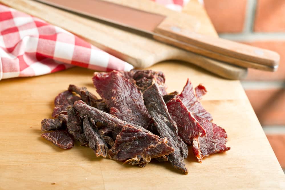 A piece of beef jerky on a wooden cutting board.