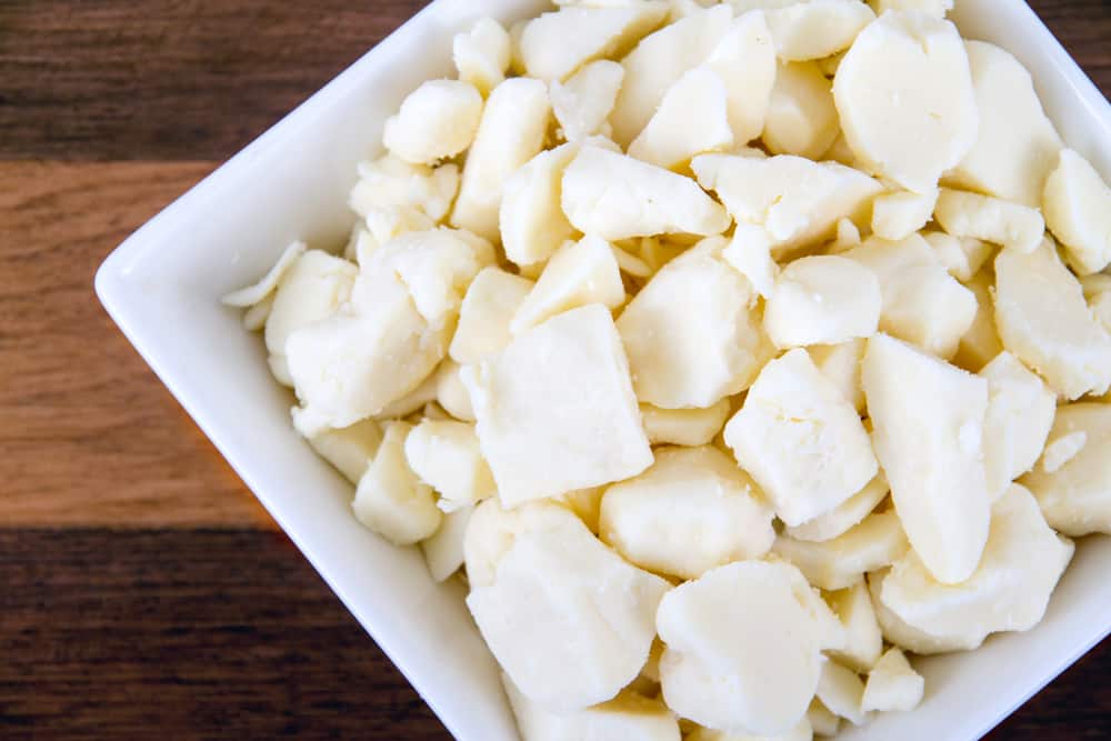 A white bowl of chopped white chocolate on a wooden table.