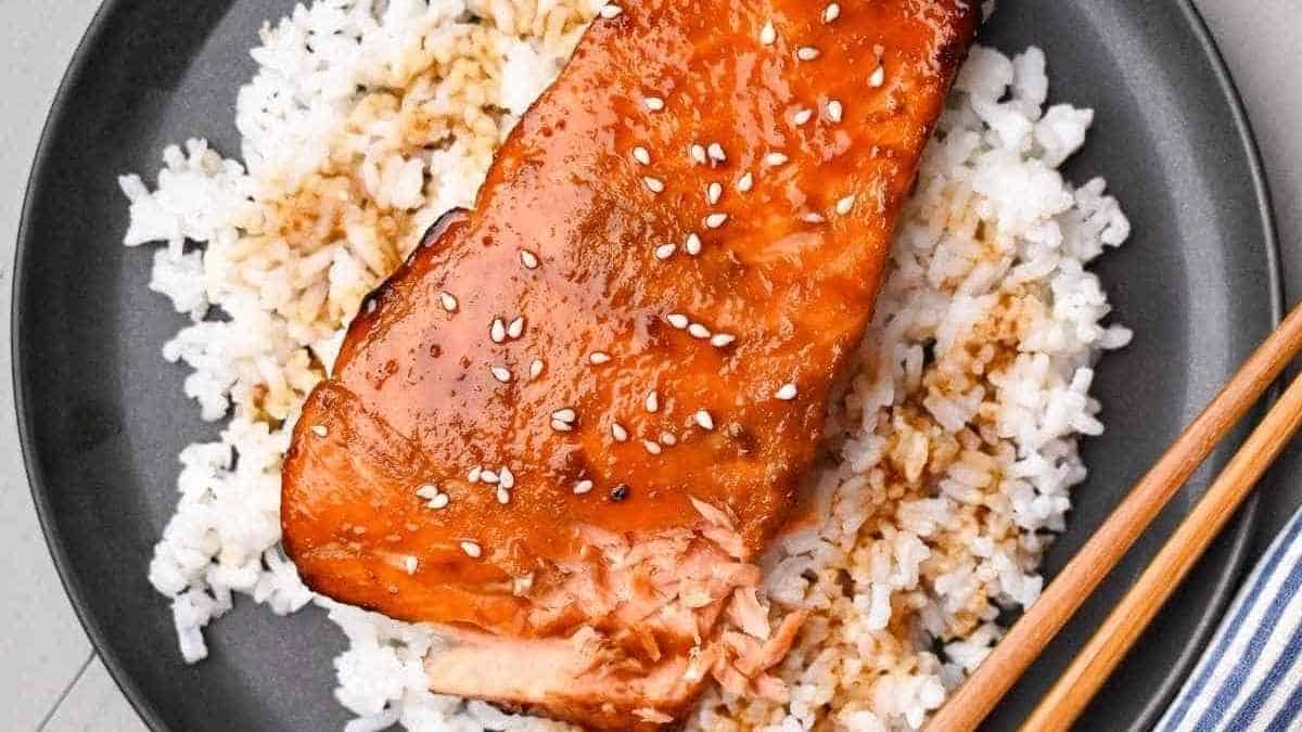 Salmon on a plate with rice and chopsticks.