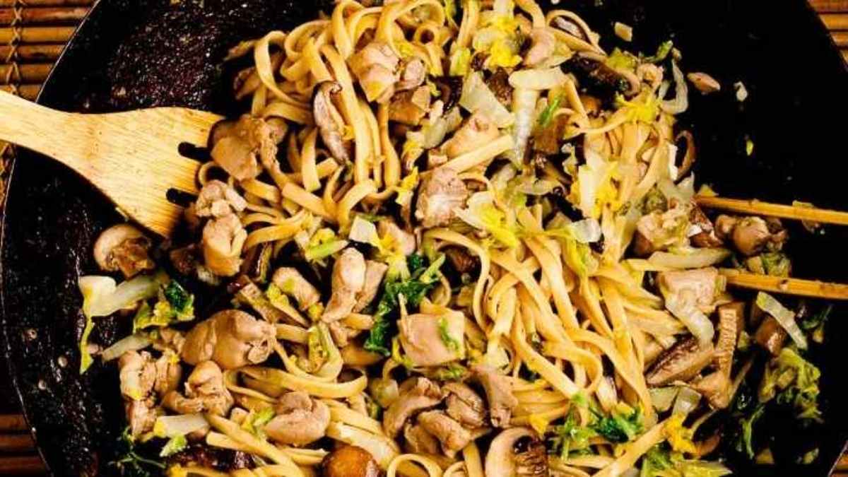 A pan with noodles and mushrooms in it.