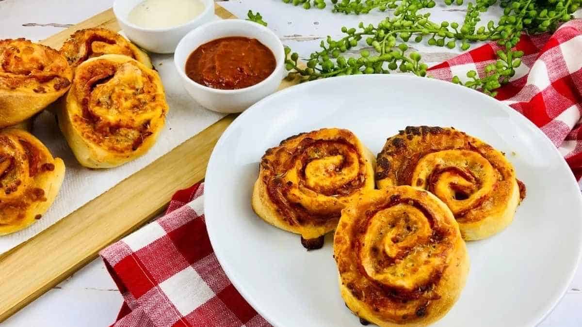 Cheesy pizza rolls on a plate with dipping sauce.