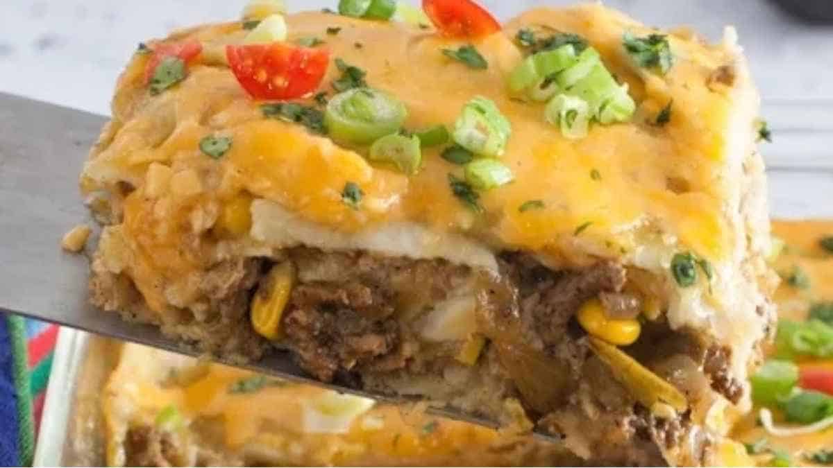 A slice of cheesy mexican casserole being taken out of a dish.