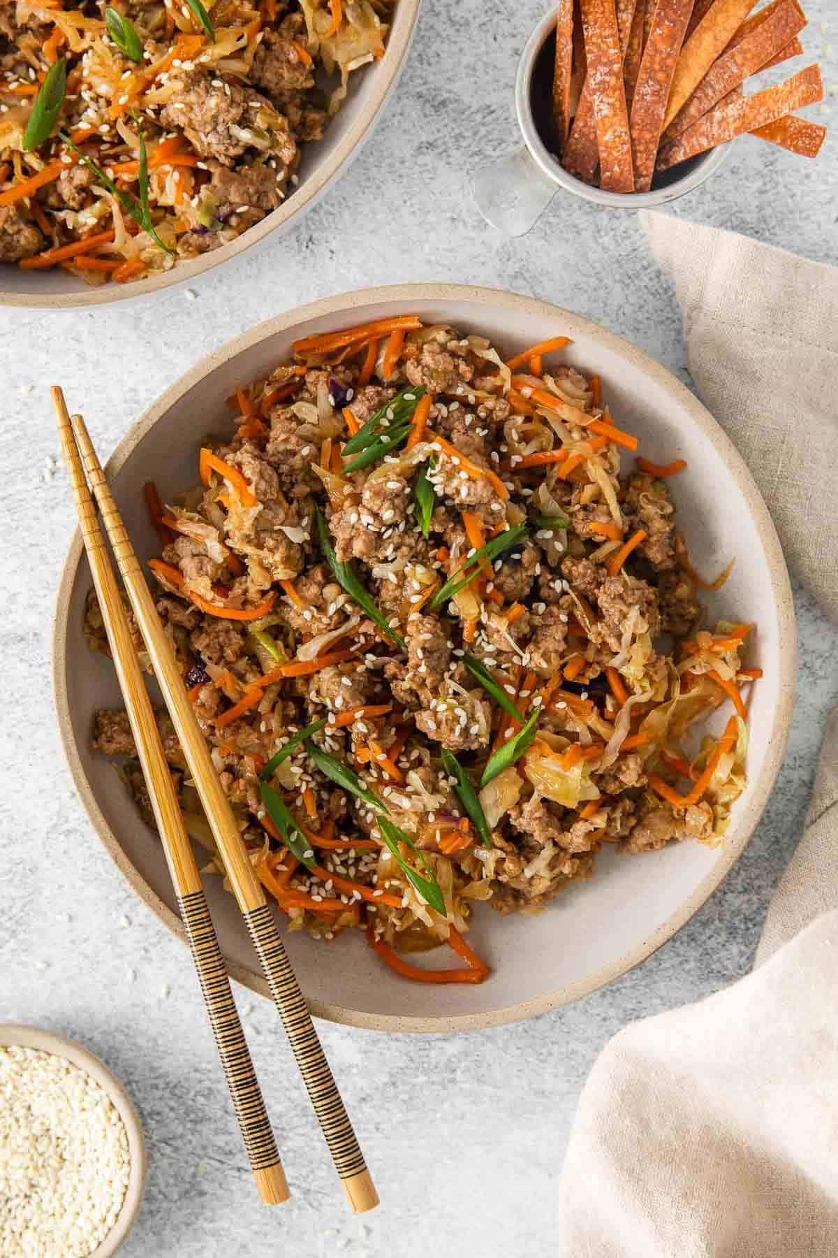 A bowl of asian fried rice with carrots and meat.