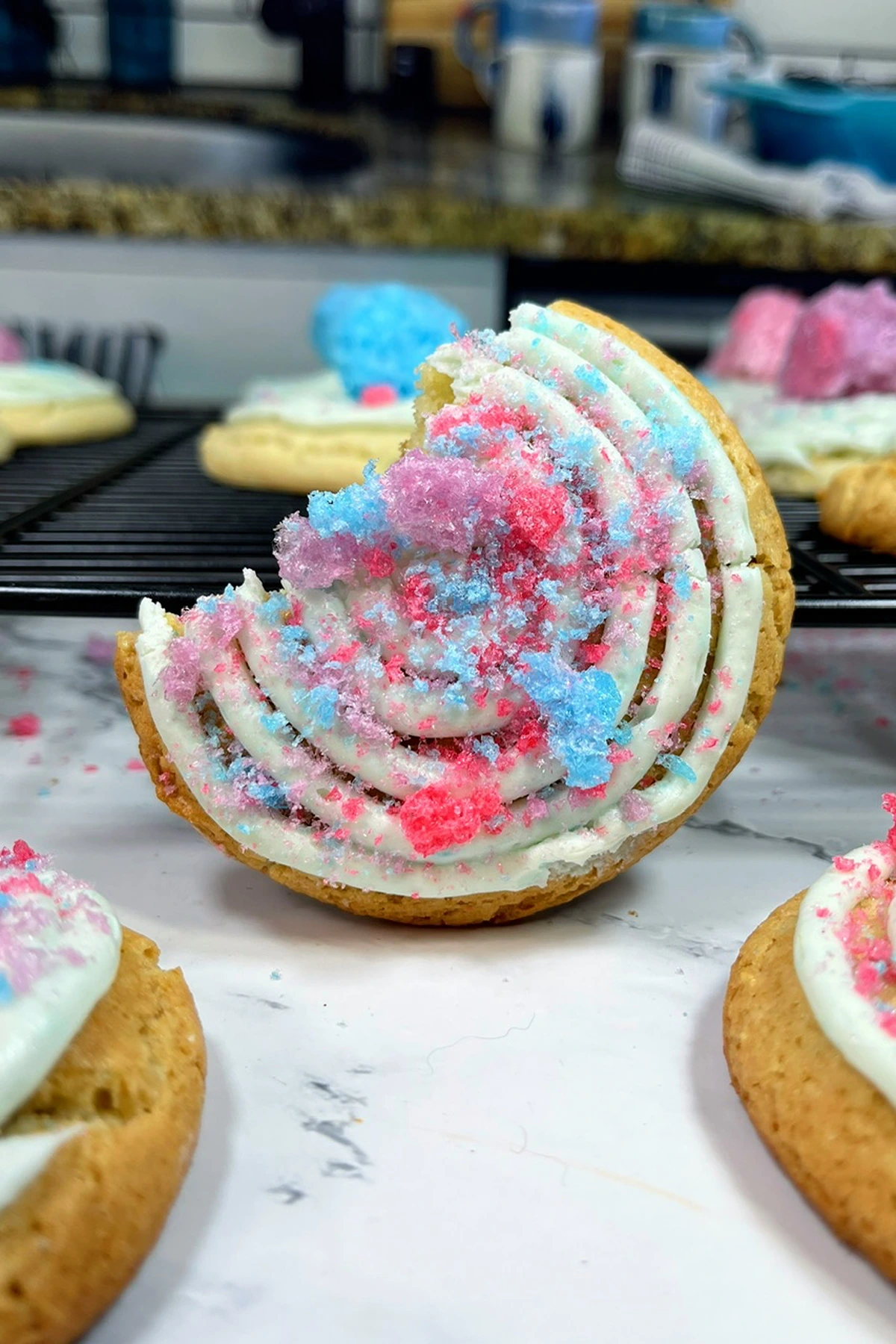 Pink and blue frosted cookies on a cooling rack, showcasing unique cookie recipes.