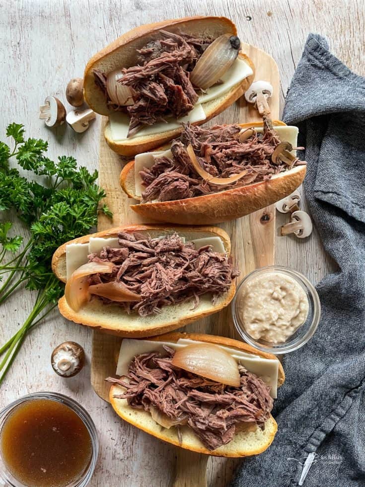 top view of french onion french dip sandwiches on wooden cutting board.
