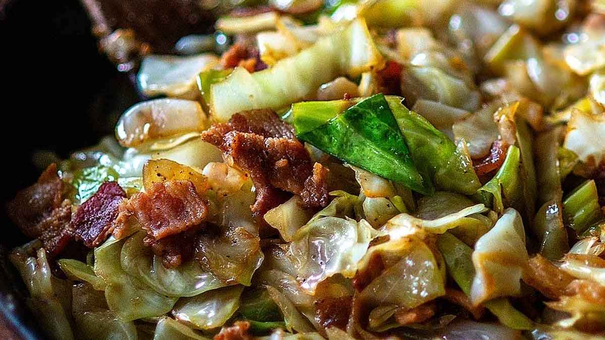 A close up of bacon and cabbage in a skillet.