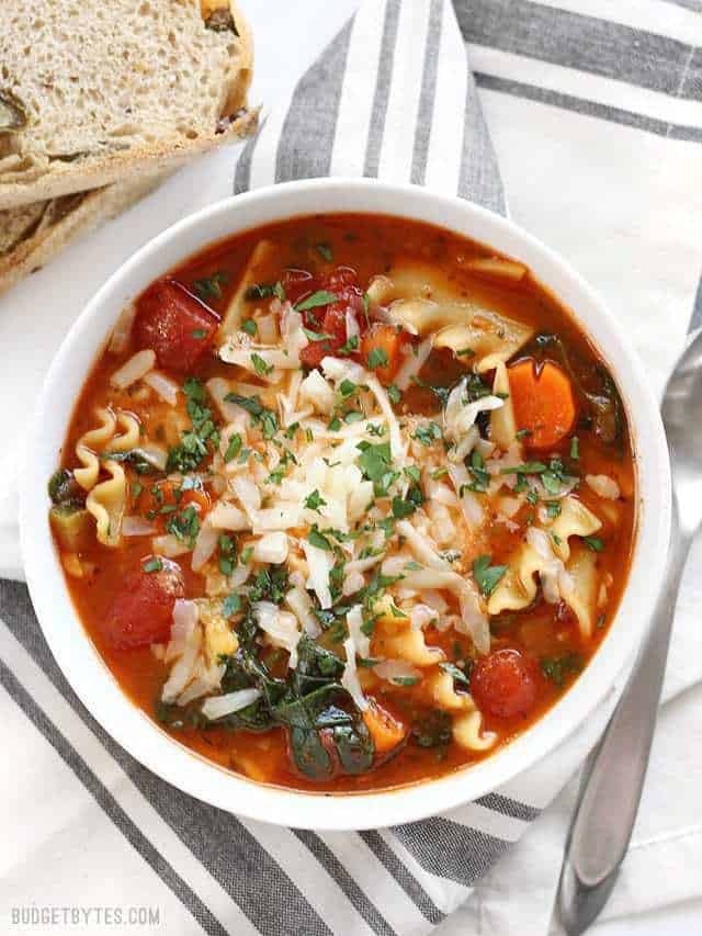 Overhead view of a bowl full of Garden Vegetable Lasagna Soup with crusty bread on the side / This Garden Vegetable Lasagna Soup is packed full of vegetables and lasagna flavor, plus a hidden dollop of melty three cheese ricotta blend in the middle! 
